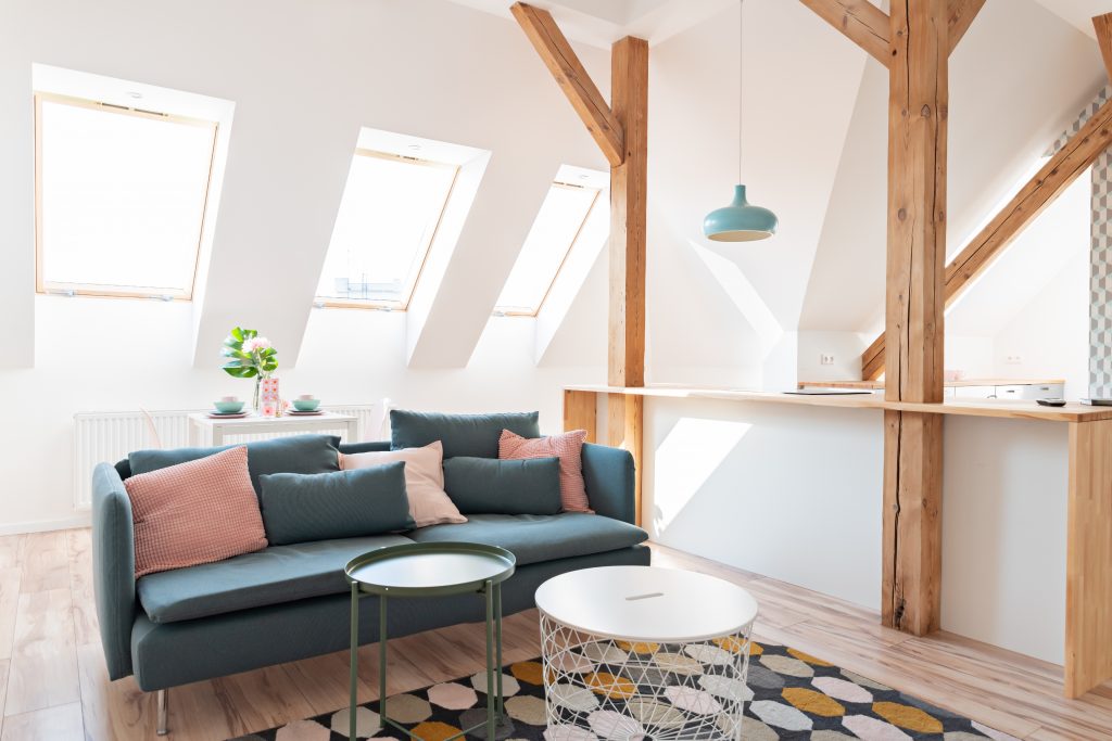 Helle Dachgeschosswohnung mit großen Fenstern, sichtbaren Holzbalken und modernem Interieur.