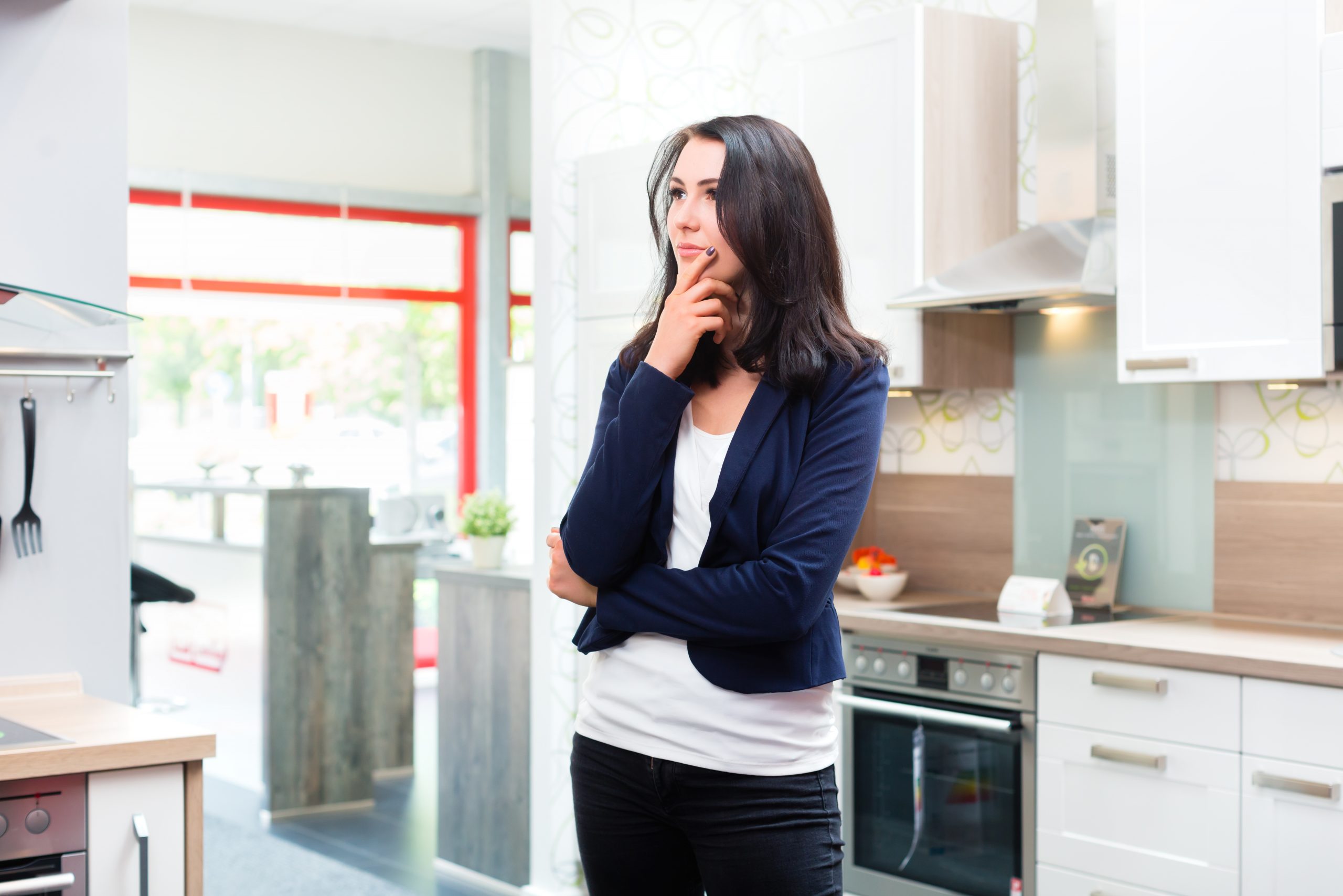 Frau steht in Küche und überlegt