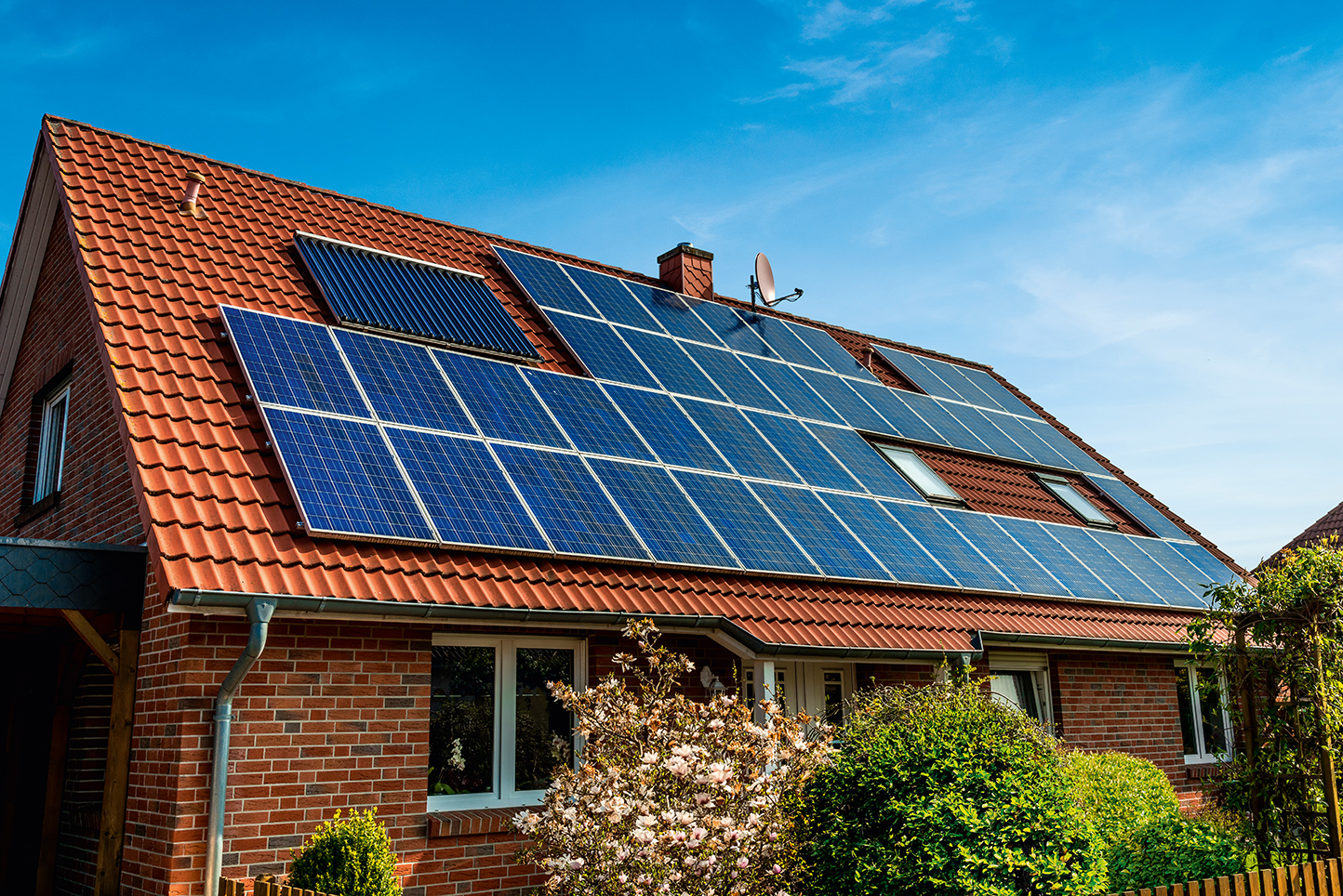 Einfamilienhaus mit Solaranlage auf dem Dach bei sonnigem Wetter