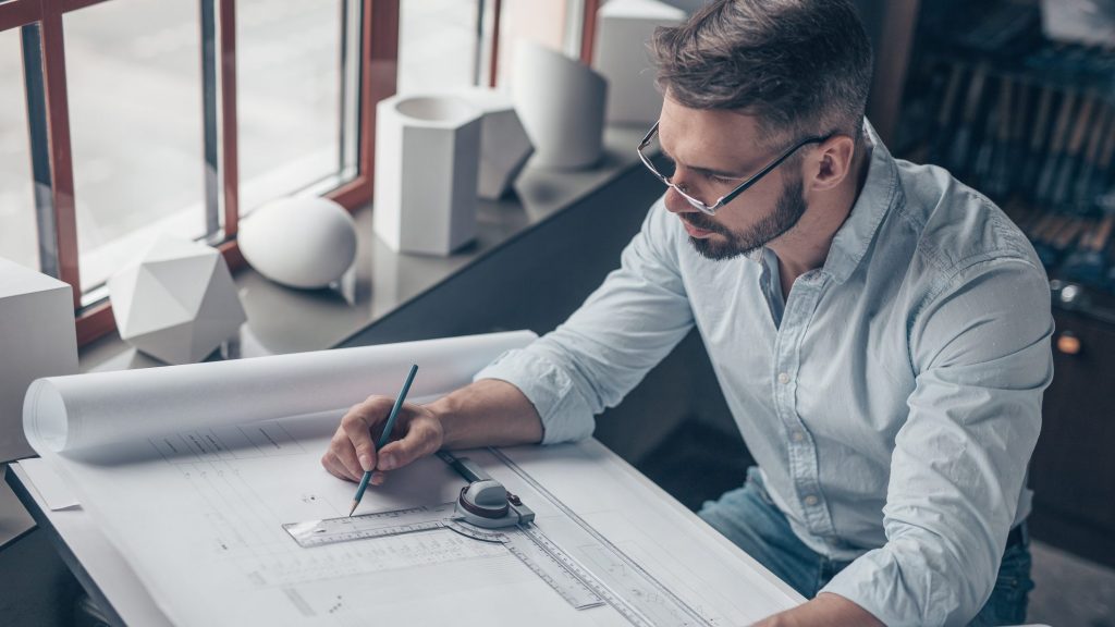 Mann mit Zeichnungen am Arbeitsplatz