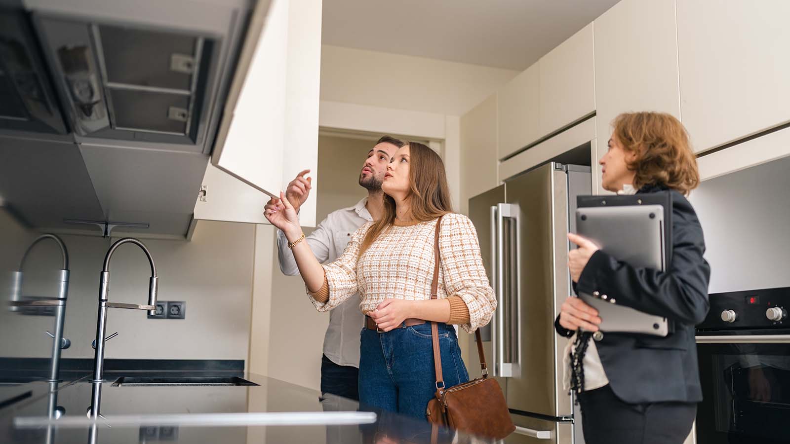 Immobilienmaklerin zeigt dem jungen Paar eine Küche in einer Wohnung
