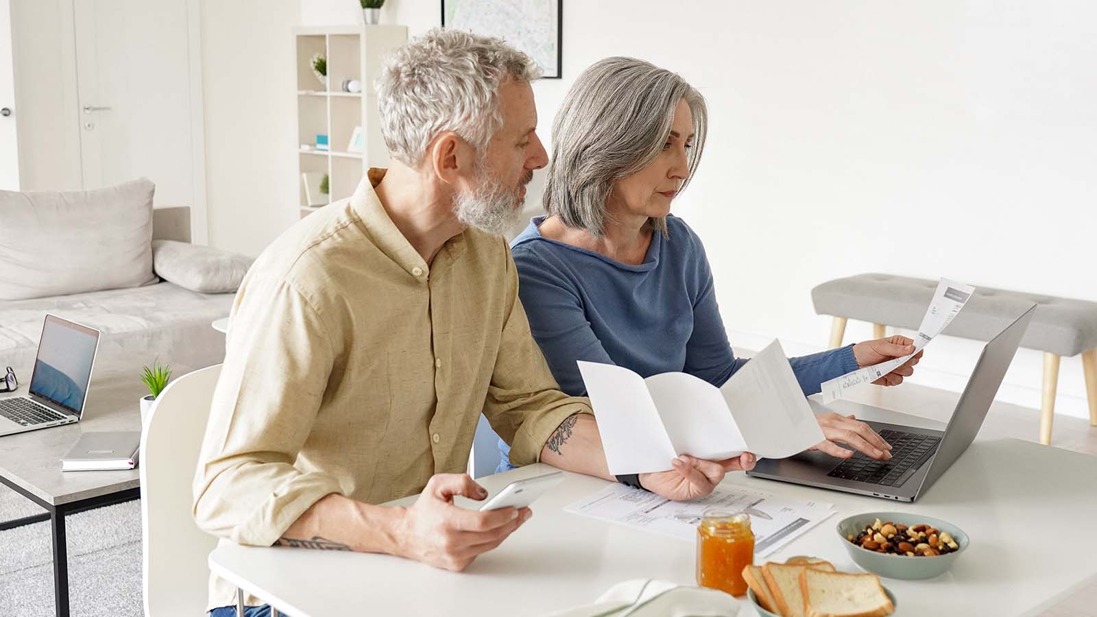 Paar sitzt mit Unterlagen am Laptop