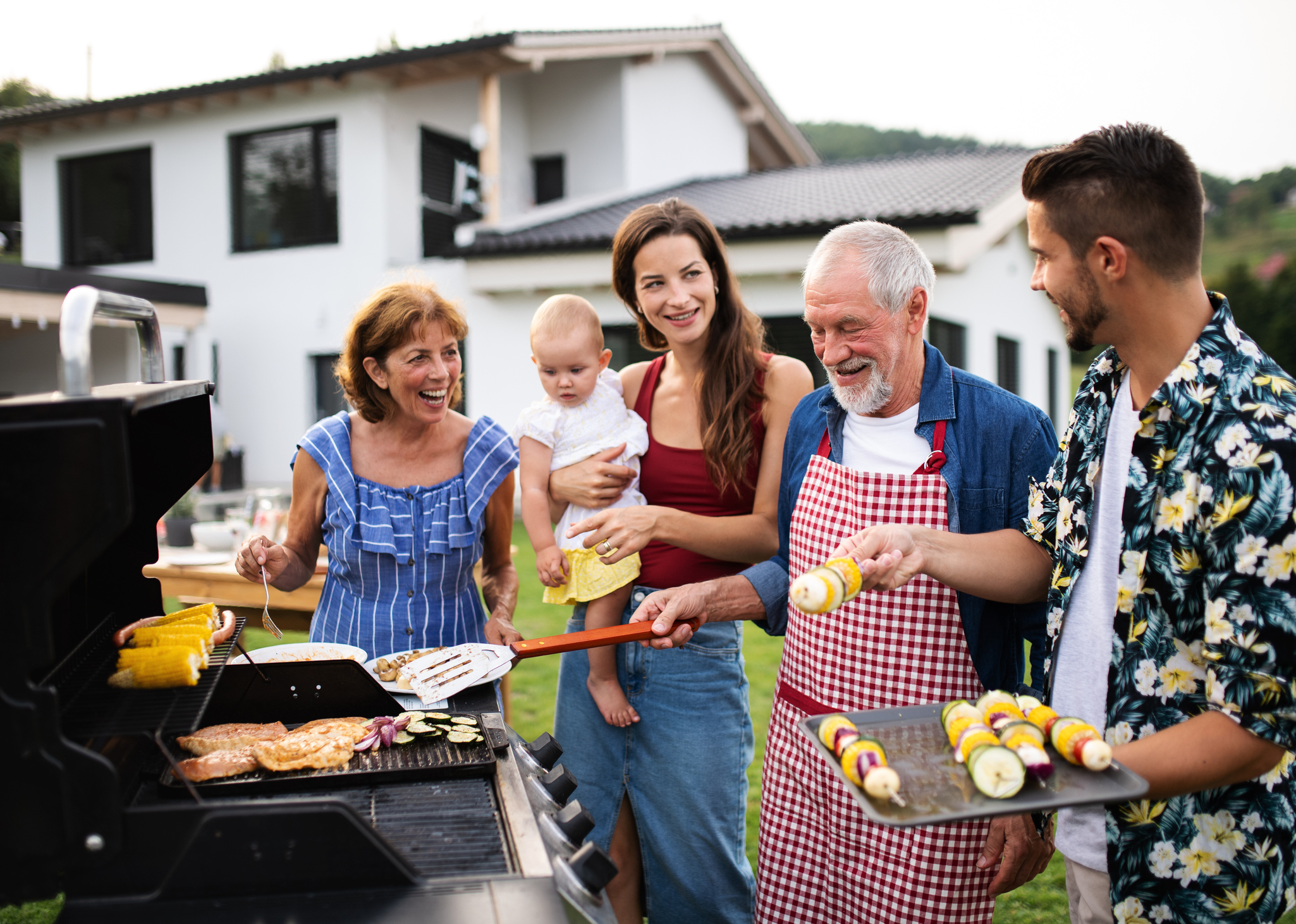 Porträt der Mehrgenerationenfamilie im Freien beim Grillen.