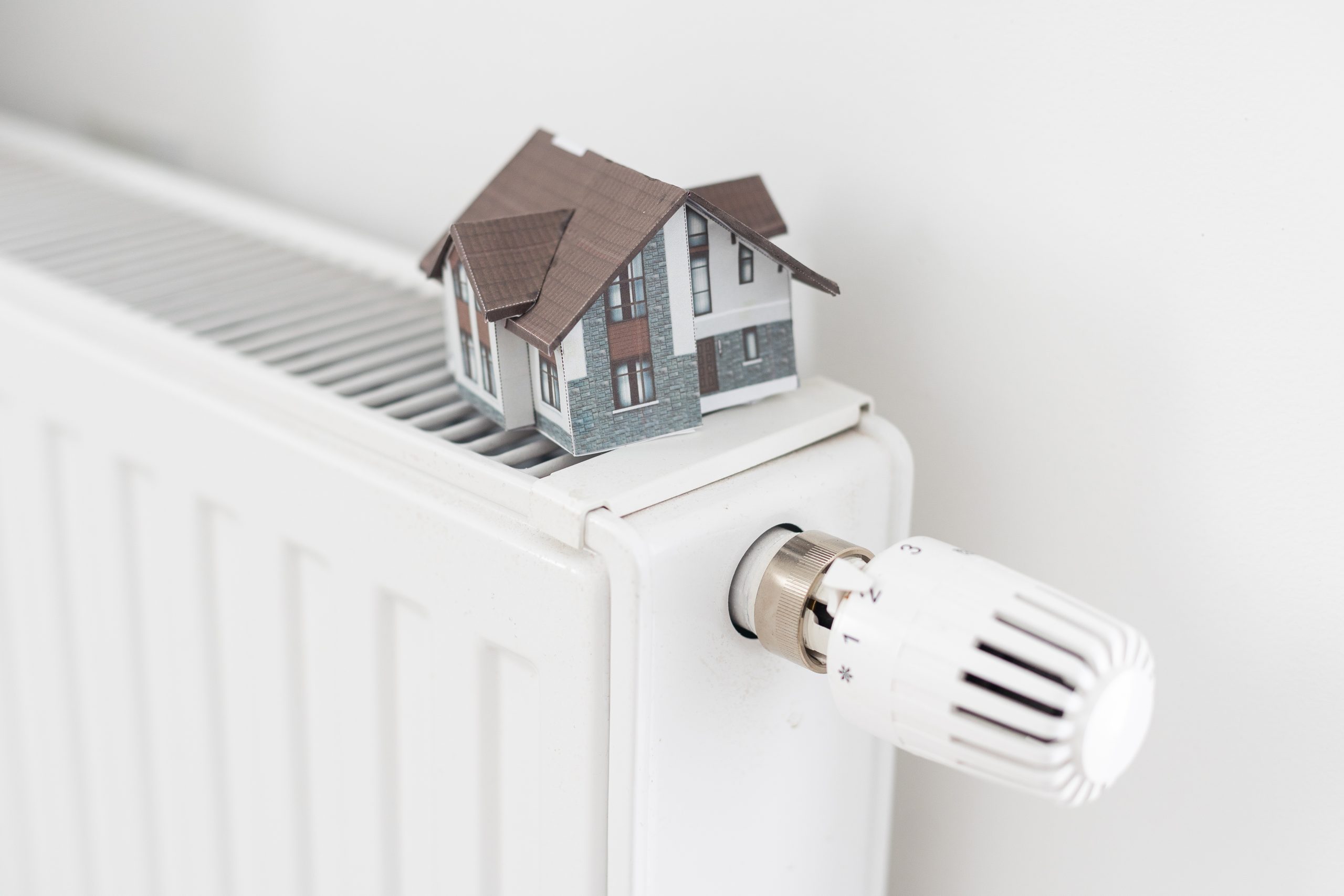 Hausmodell in Miniatur steht auf Heizkörper